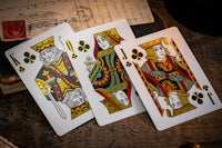 three playing cards on a wooden table